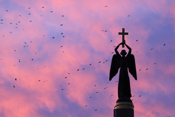 Birds fly near a statue of an angel holding a cross, the symbol of the city, at sunset in Stavropol, Russia in this Nov. 2010 file photo. (CNS photo/Eduard Korniyenko, Reuters)