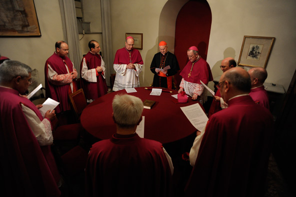 Italian Cardinal Tarcisio Bertone, center with red skull cap, prays with assistants as the ceremonies and tasks of the "sede vacante" begin at the Vatican Feb. 28. The red velvet-covered scepter before him is the symbol of his authority as camerlengo or chamberlain. He is charged with administering the temporal goods of the church following the resignation of Pope Benedict XVI. (CNS photo/L'Osservatore Romano via Catholic Press Photo)