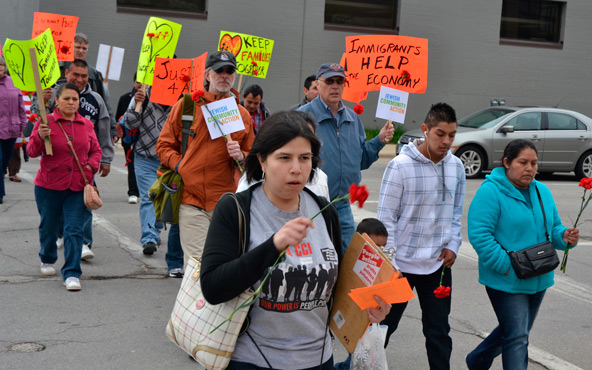 Carrying red flowers representing the 389 workers arrested in a 2008 immigration raid on an Iowa plant, hundreds of people participate in a Walk for Justice and interfaith prayer service May 10 in Cedar Rapids, Iowa. The participants were commemorating t he fifth anniversary of the raid on the Agriprocessors Plant in Postville, which continues to have an impact far beyond the small town in a rural corner of the Dubuque Archdiocese. (CNS photo/Dan Russo, The Witness)