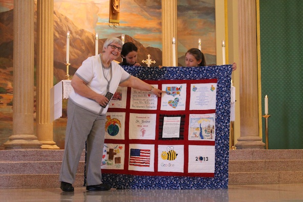 Benedictine Sister Josine points out some of the symbolism and craftsmanship that went into creating a quilt as part of her retirement gift. St. Thomas the Apostle students and staff presented it on the final day of school June 7. (Ambria Hammel/CATHOLIC SUN)