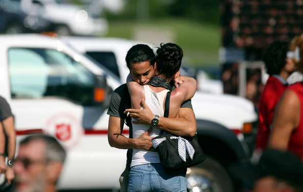 A man consoles a friend July 8 at the Polyvanlente Montignac, the school sheltering people who were forced to flee their houses after a train explosion in Lac-Megantic, Quebec. Most of the town's central business district and dozens of residences were de stroyed July 6 after a runaway train that was headed to a New Brunswick oil refinery derailed and exploded. (CNS photo/Mathieu Belanger, Reuters)