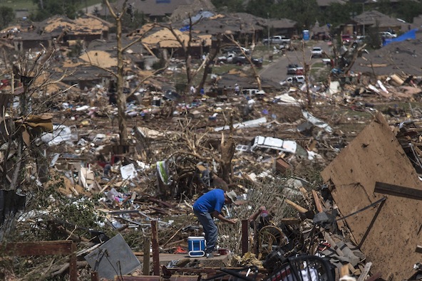 A man prepares to sit on a cooler while taking a lunch break on the foundation of his flattened home in Moore, Okla., May 21, the day after a massive tornado devastated the town. (CNS photo/Adrees Latif, Reuters)