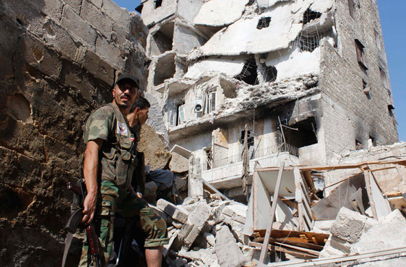 Free Syrian Army fighters stand in front of buildings damaged by what activists said was shelling by forces loyal to Syrian President Bashar Assad in the old city of Aleppo Sept. 2. During the Sept. 1 Angelus, Pope Francis announced he would lead a world wide day of fasting and prayer for peace in Syria Sept. 7. (CNS/Molhem Barakai, Reuters)