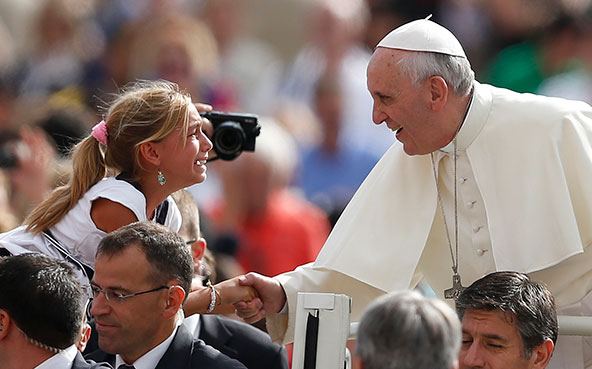 Pope Francis shakes hands with a girl as he arrives to lead his general audience in St. Peter's Square at the Vatican Sept. 11. (CNS photo/Paul Haring)
