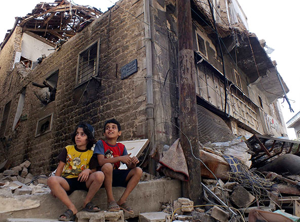 Children sit along a damaged street filled with debris in the besieged area of Homs, Syria, Sept. 19. Two bombings a day later killed at least 39 people in the latest surge in violence. (CNS photo/Yazan Homsy, Reuters)