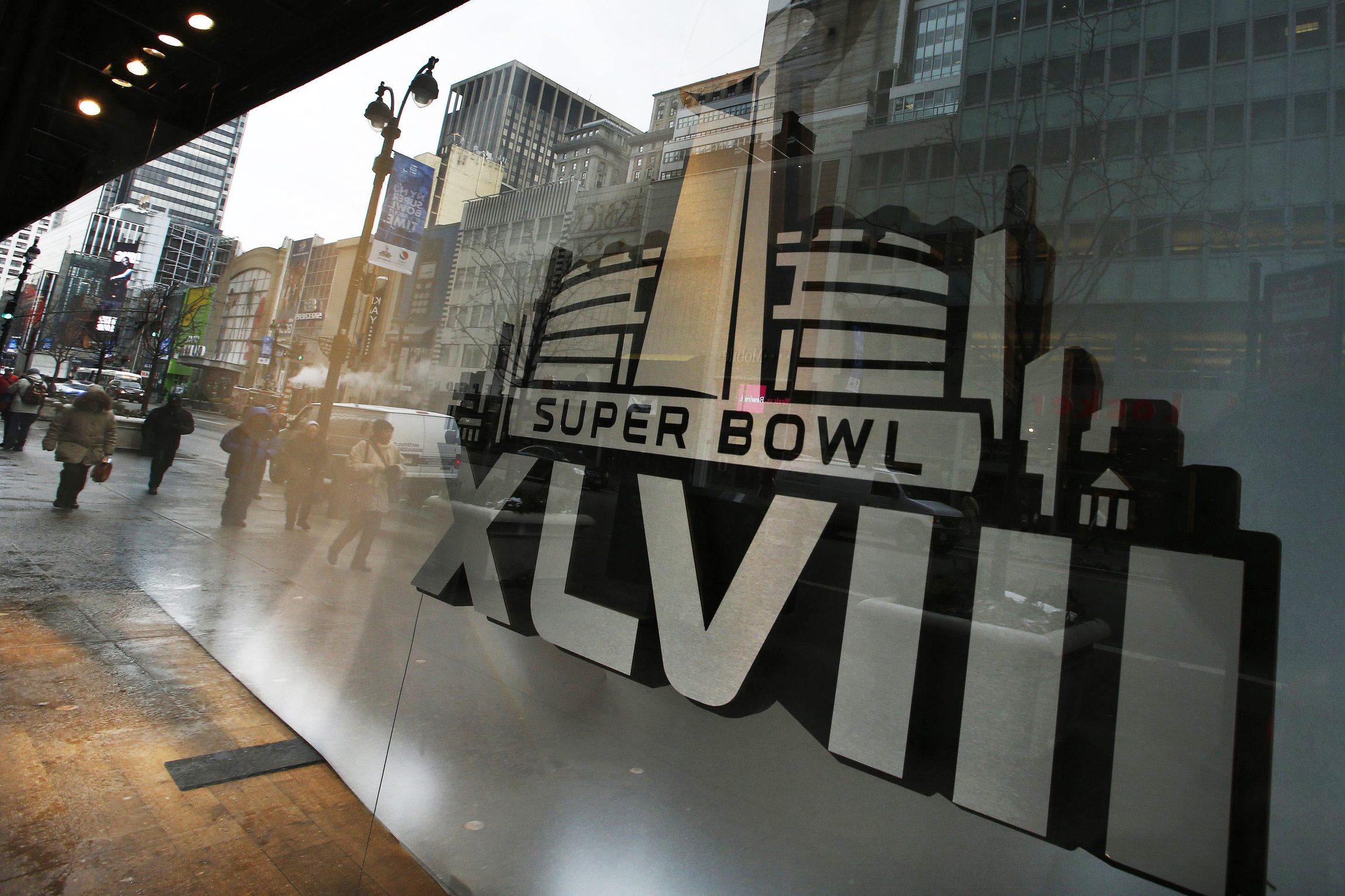 Pedestrians are reflected on windows displaying the Super Bowl icon Jan. 27 as preparations continued for Super Bowl XLVIII in New York. Margot Morris, program director for the Tri-State Coalition for Responsible Investment, says a lot of "positive feedback" has been reported from hotels expecting an influx of visitors for the Feb. 2 Super Bowl regarding efforts to curb human trafficking, primarily sex trafficking, surrounding the event. (CNS photo/Eduardo Munoz, Reuters)