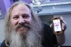 Francis Richardson shows off his new smile at St. Vincent de Paul's adult dental clinic Feb. 26 while showing a photo of himself when the only teeth he had were made of paper. (Ambria Hammel/CATHOLIC SUN)