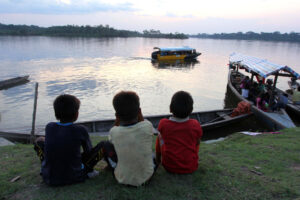 Kukama boys watch boats on the Maranon River near the community of Dos de Mayo in Peru's Loreto region. Water, soil and sediments in the Amazon tributary contain heavy metals and other residue from more than four decades of oil production. In all 17 comm unities tested, the rivers, lakes or wells that provide drinking water were deemed unsafe. (CNS photo/Barbara Fraser)