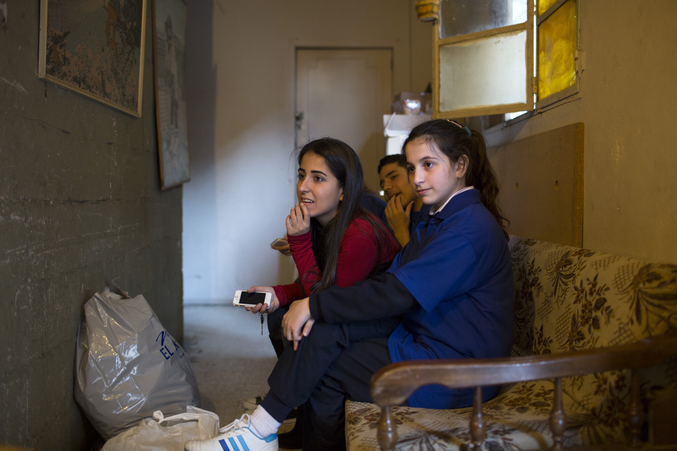 Students from St. George School in the Zalka section of Beirut listen to Nayla, not pictured, during a Youth of Life visit March 14. The students were distributing aid to the widow. (CNS photo/Dalia Khamissy)