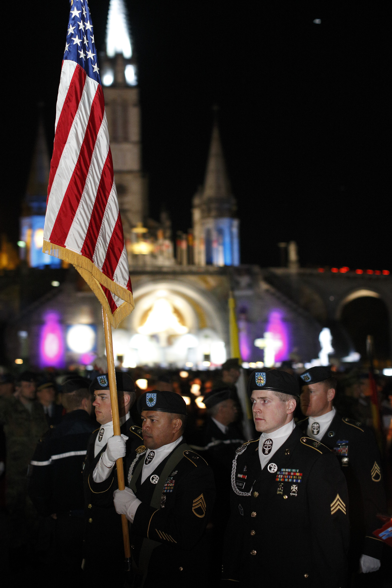 The U.S. flag is carried in procession as military personnel leave after a candlelight vigil at the Shrine of Our Lady of Lourdes in southwestern France May 17. About 60 wounded U.S. military personnel, together with family members and caregivers, were a part of the annual International Military Pilgrimage to Lourdes. (CNS photo/Paul Haring)