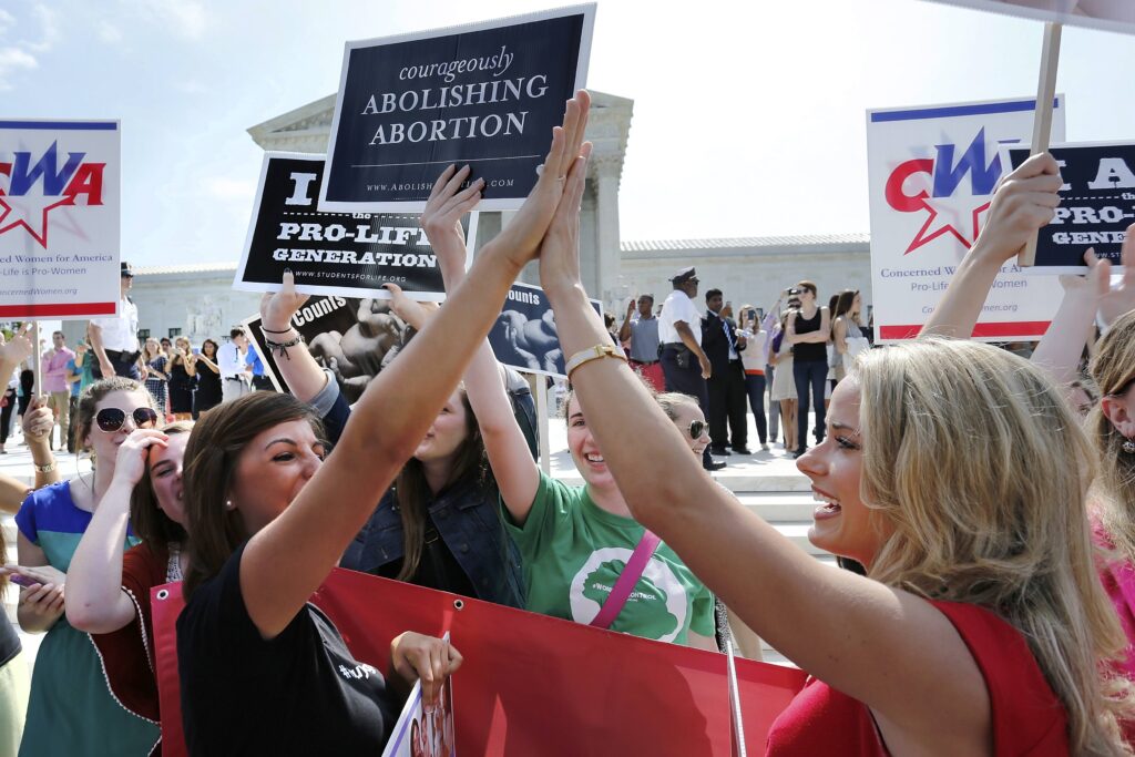 Pro-life demonstrators celebrate June 30, 2014, outside the U.S. Supreme Court in Washington as its decision in the Hobby Lobby case is announced. The high court ruled that owners of closely held corporations can object on religious grounds to being forced by the government to provide coverage of contraceptives for their employees. (CNS photo/ Jonathan Ernst)