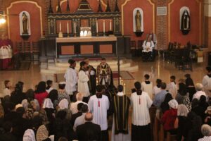 Fr. Terra, with both hands and arms bandaged, sits in a wheelchair to the right of the altar at the requiem Mass days after the attack. 