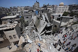 Palestinians in Rafah, Gaza Strip, gather around the remains of a house that police said was destroyed in an Israeli airstrike. Israel said it shot down a drone from Gaza July 14, the first reported deployment of an unmanned aircraft by Palestinian militants whose rocket attacks have been regularly intercepted. (CNS photo/Ibraheem Abu Mustafa)