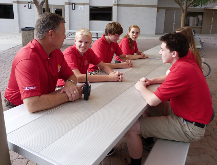 Jack Barten, new campus security specialist at Seton Catholic Preparatory, talks with freshmen students. The addition of a campus security officer and crisis management system increased campus communication efforts to track visitors and suspicious activity. (courtesy photo)