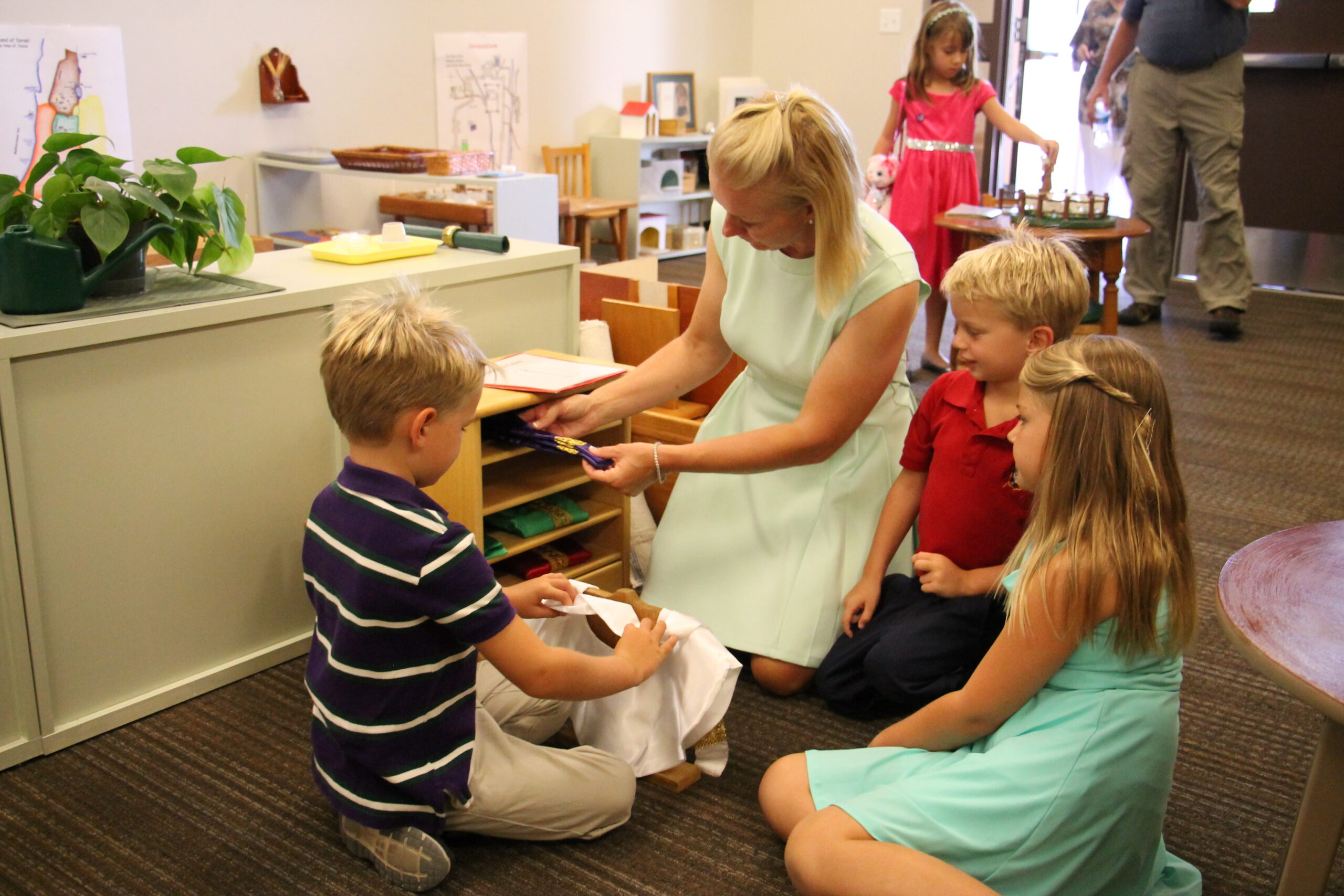 An Our Lady of Perpetual Help family gets a hands on look at priest vestments and the meaning of their colors Aug. 24 inside the parish atrium. Creating a child-friendly environment is key in the Catechesis of the Good Shepherd program and other faith formation models. (Ambria Hammel/CATHOLIC SUN)
