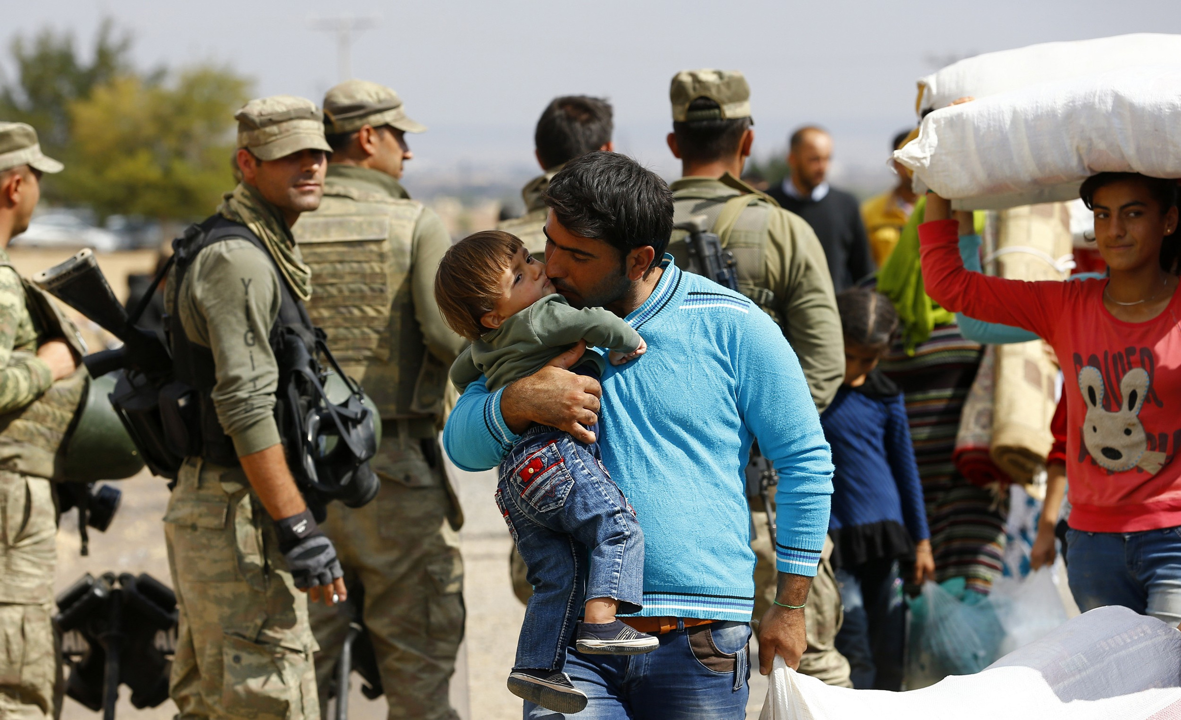 A Syrian Kurdish family walks through a border crossing Sept. 29 to return to their home in the Syrian city of Kobani, on the Turkish-Syrian border. A Syrian priest on a U.S. mission trip says amid ongoing death and destruction in the Middle East, the Catholic Church continues to provide spiritual and material support for those in need. (CNS photo/Murad Sezer, Reuters)