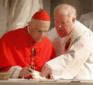 Father Michael Hack, a judge on the Chicago Archdiocese's metropolitan tribunal, assists Cardinal Francis E. George Sept. 29 in signing the final documents for the sainthood cause for Fr. Augustus Tolton during a prayer service in Chicago. The dossier was dispatched to the Vatican Congregation for Saints' Causes. (CNS photo/Karen Callaway, Catholic New World)