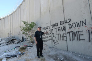 Retired Bishop Michael D. Pfeifer of San Angelo, Texas, stands in front of the Israeli separation wall near Jerusalem Sept. 12. Bishop Higgins was one of 18 bishops on a nine-day prayer pilgrimage for peace in the Holy Land. (CNS photo/Debbie Hill)
