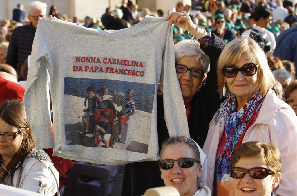 A woman holds a shirt with a photo of children before Pope Francis' encounter with the elderly in St. Peter's Square at the Vatican Sept. 28. (CNS photo/Paul Haring)