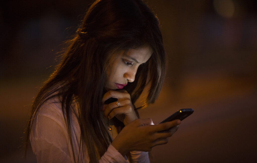 Sulemi Marcial, 14, checks her phone Nov. 20 as she waits outside the Arizona Capitol in Phoenix to see a live broadcast of President Barack Obama's national address. The president extended the deferral of deportations to parents of millions of U.S. citizens and legal residents. (CNS photo/Nancy Wiechec)