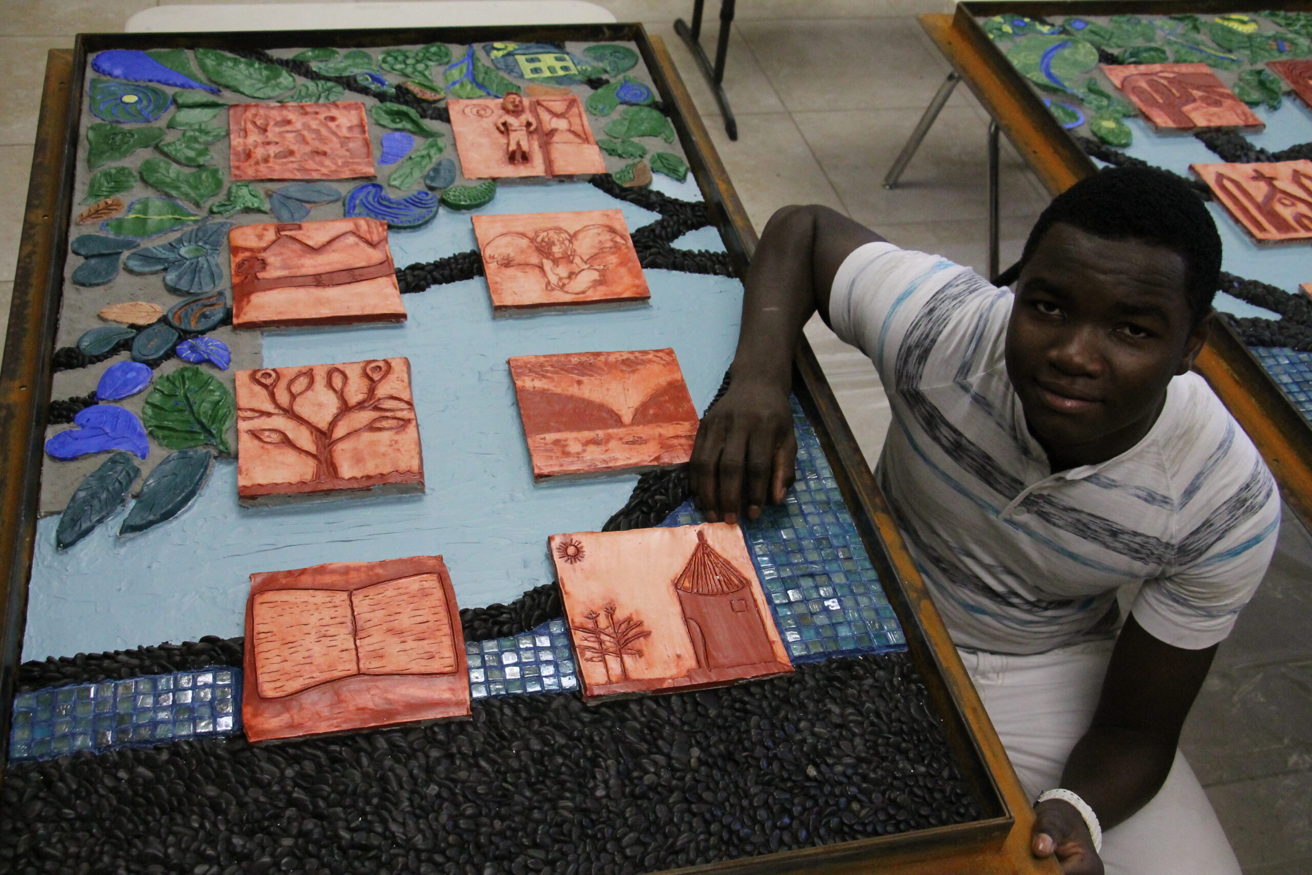 Ishak, a 19-yearold refugee from South Sudan, was one of 24 refugee youth whose carved tiles depict their memory or idea of a safe place. (Ambria Hammel/CATHOLIC SUN)