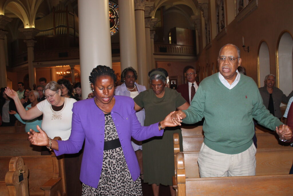 Elizabeth Mokogwu and Alcurtis Robinson pray the Our Father at the MLK Mass Jan. 19 at St. Mary's Basilica.