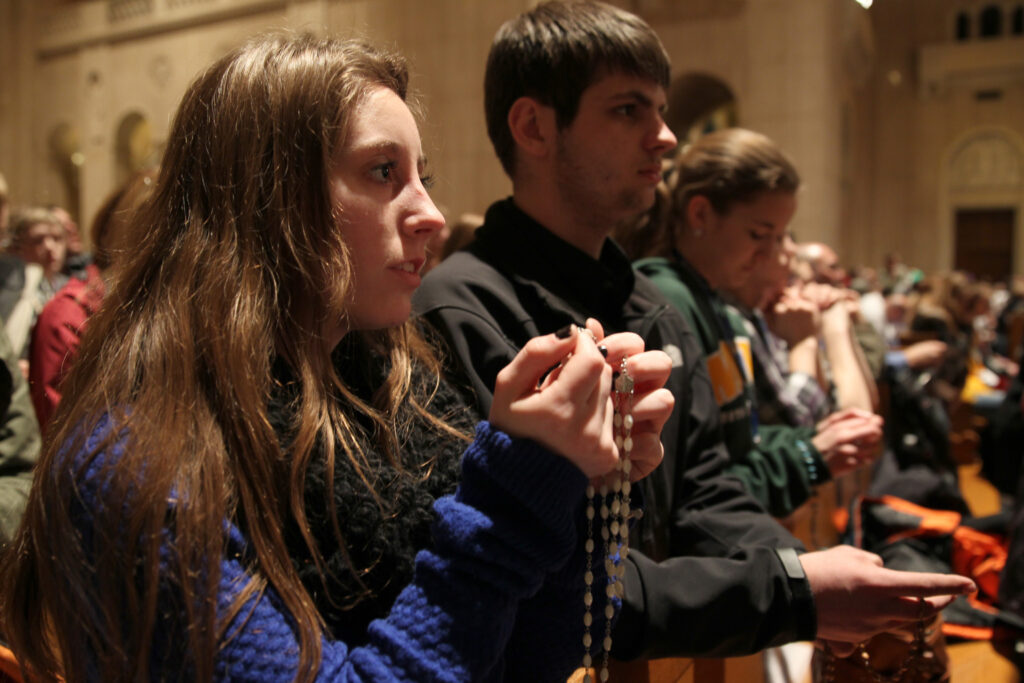 A young woman prays the rosary during the National Prayer Vigil for Life at the Basilica of the National Shrine of the Immaculate Conception in Washington Jan. 21. The all-night vigil is held before the annual March for Life, which this year marked the 42nd anniversary of the Supreme Court's Roe v. Wade decision that legalized abortion across the nation. (CNS photo/Bob Roller)