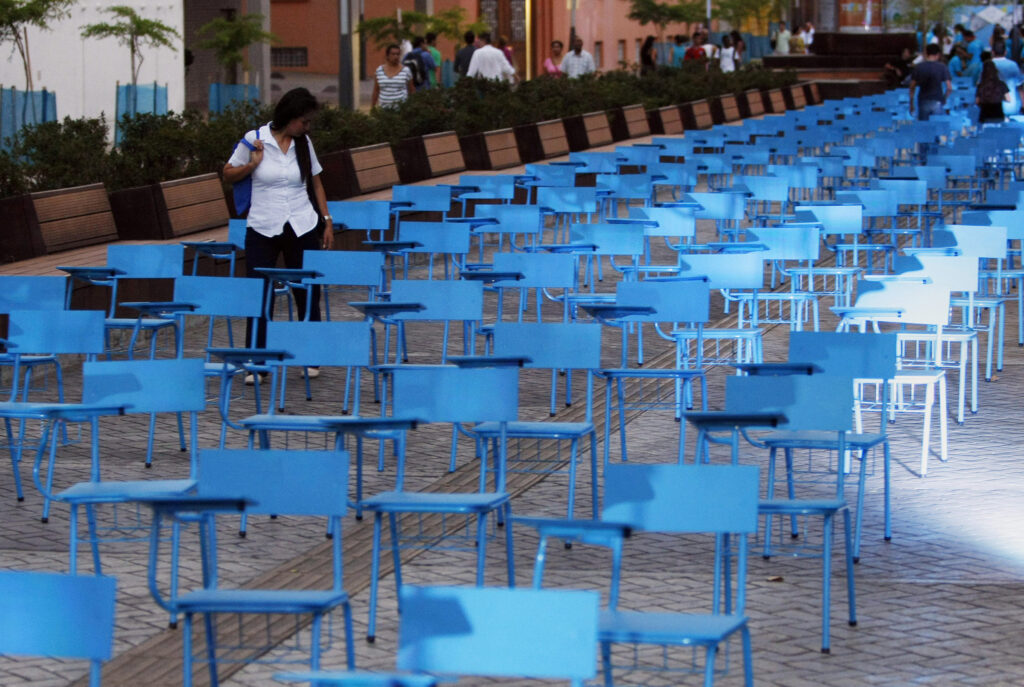 A girl walks among a blue chairs installation for Human Trafficking Awareness Day in Cali, Colombia, July 30, 2014. The chair represent more than 20 million men, women and children who are victims of human trafficking worldwide. (CNS photo/Christian Escobar Mora, EPA)
