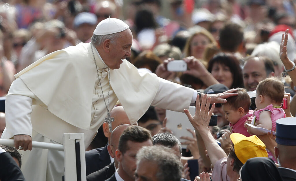 Pope Francis greets a baby as he arrives to lead his general audience in St. Peter's Square at the Vatican May 20. (CNS photo/Paul Haring)