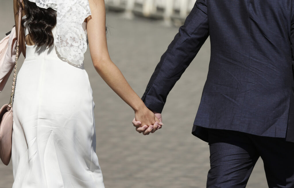 A newly married couple hold hands as they arrive for Pope Francis' general audience in St. Peter's Square at the Vatican May 27. (CNS photo/Paul Haring)