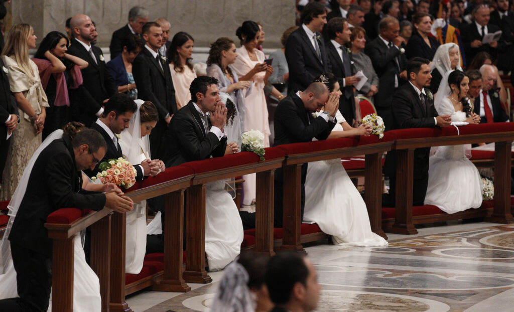 Newly married couples kneel as Pope Francis celebrates the marriage rite for 20 couples during a Mass in St. Peter's Basilica at the Vatican Sept. 14, 2014. (CNS photo/Paul Haring)