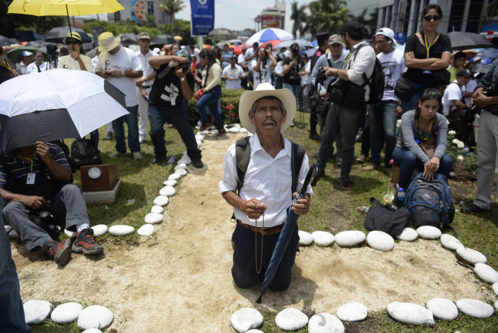 Pilgrim prays to Archbishop Oscar Romero during beatification Mass May 23 in the Divine Savior of the World square in San Salvador. (CNS photo/Lissette Lemus) 