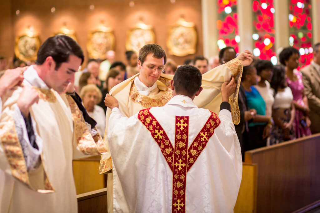 Newly ordained deacons Ryan Lee and David Loeffler receive their vestments during their ordination May 31 Mass at Ss. Simon and Jude Cathedral. (Billy Hardiman/CATHOLIC SUN)