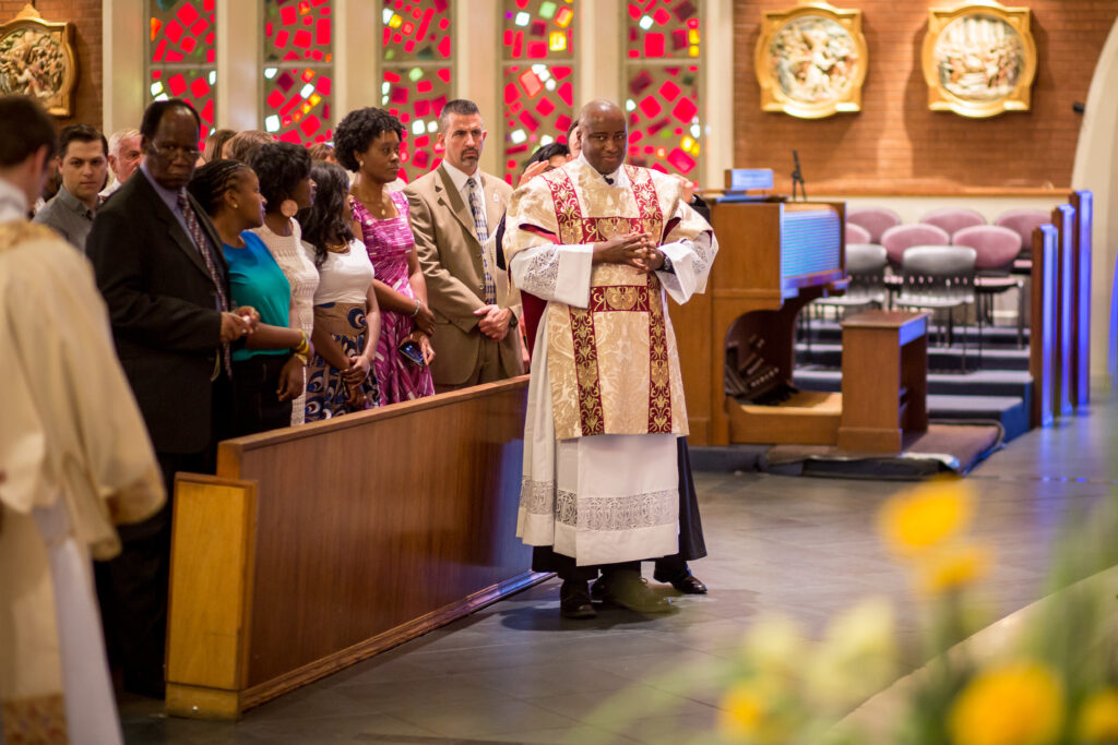 Dcn. Sheunesu Bowora stands in front of his family after being vested during the May 31 ordination Mass at Ss. Simon and Jude Cathedral. (Billy Hardiman/CATHOLIC SUN)