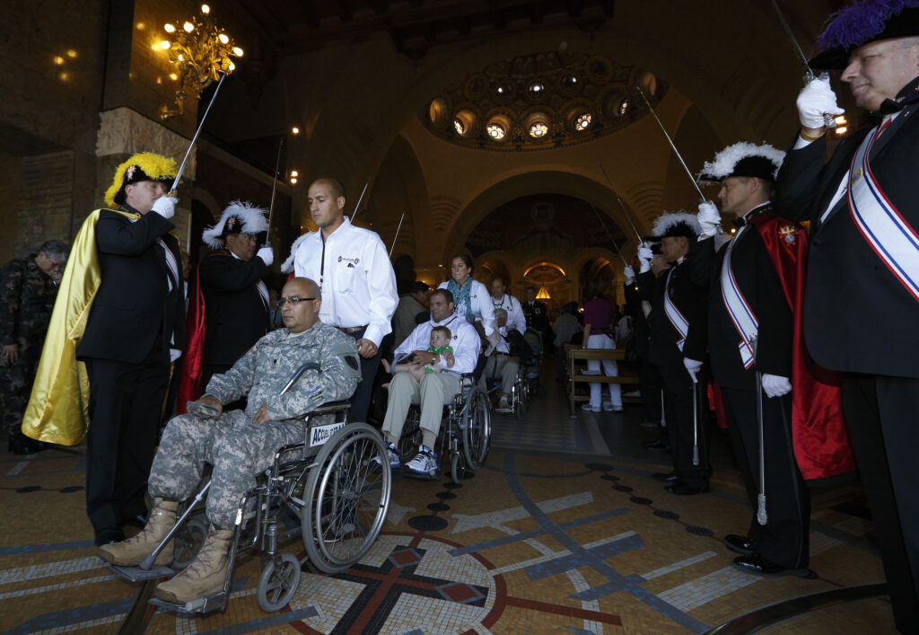 Members of the Knights of Columbus hold swords as U.S. military personnel leave in wheelchairs after a Mass at the Shrine of Our Lady of Lourdes in southwestern France May 16. (CNS photo/Paul Haring) 