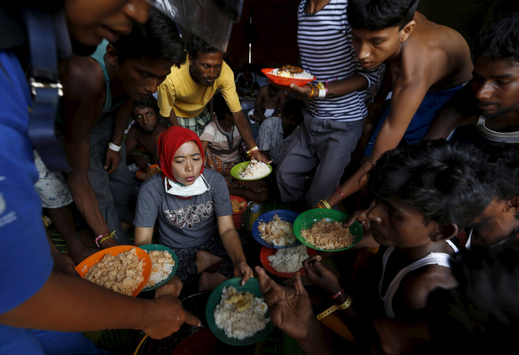 Bangladeshi migrants raise up their plates to ask for more food as breakfast is served by volunteers at a shelter in Kuala Langsa, in Indonesia's Aceh Province, May 19. Pope Francis said people must stop wasting, start sharing food and other resources. (CNS photo/Beawiharta)