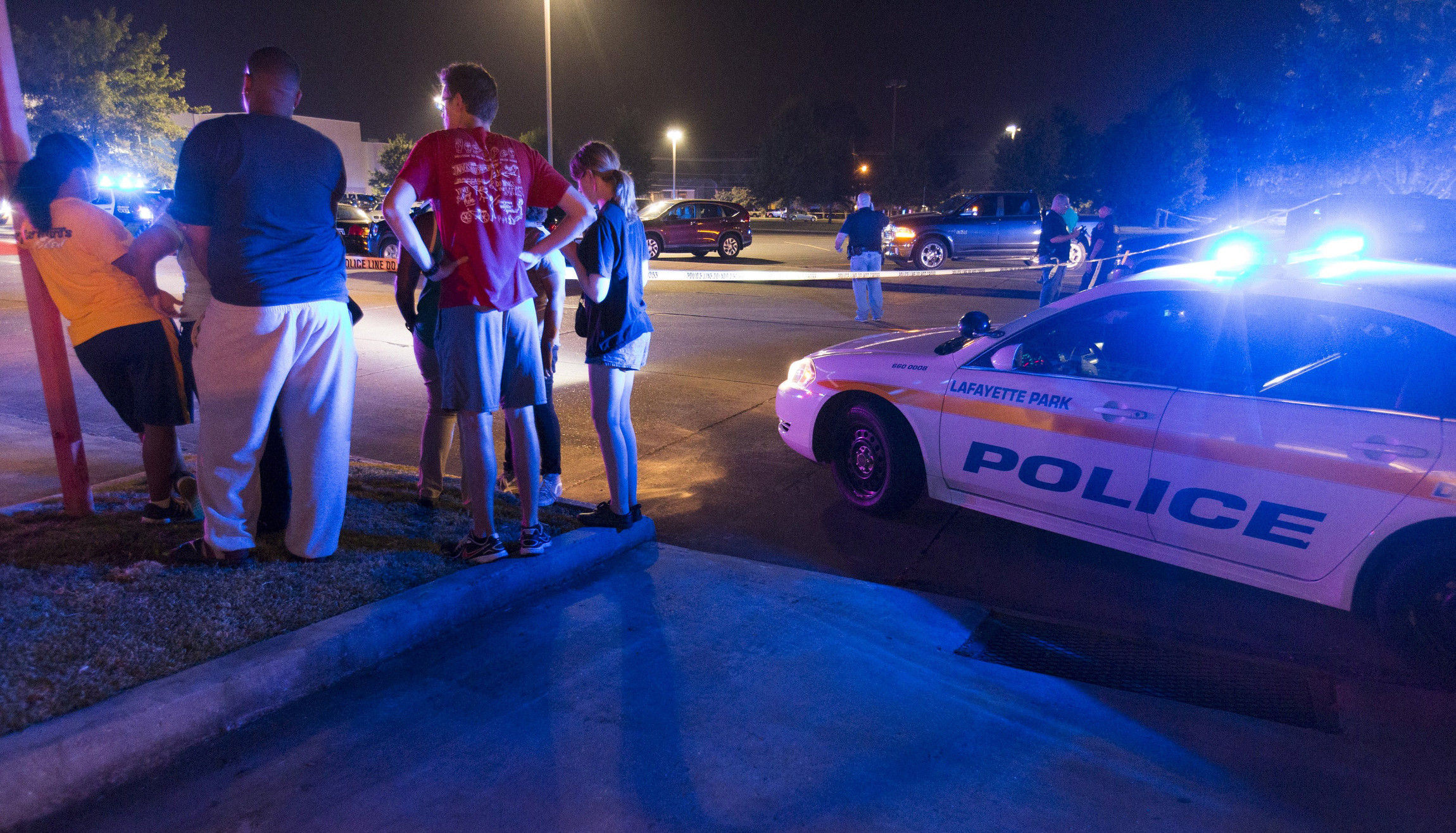 Bystanders watch over the scene at a movie theater in Lafayette, La., July 23. A gunman opened fire at the theater that evening, killing at least two people and injuring nine others before taking his own life, according to local reports. (Lee Celano/CNS via Reuters)