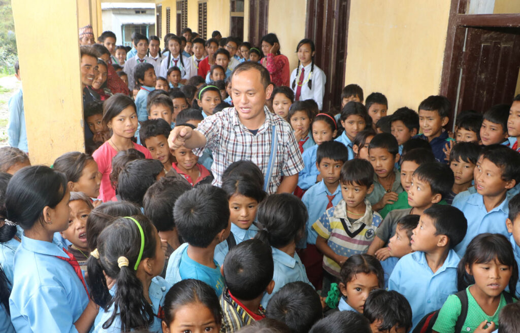 Salesian Father Savio Rai entertains students at the government-run school in at Chaughare, Nepal, July 9. A magnitude 7.8 earthquake April 25 destroyed more than 25,000 classrooms in nearly 8,000 schools. (CNS photo/Anto Akkara)