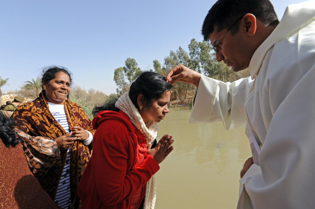 Franciscan Brother Praveen of India sprinkles a pilgrim with water by the Jordan River during Mass at Qasr el-Yehud in celebration of the feast of the Baptism of the Lord in this 2012 file photo. (CNS photo/Debbie Hill)