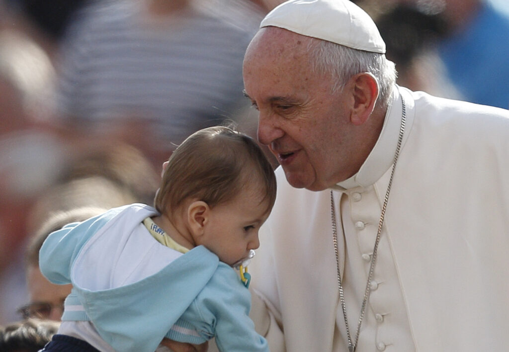 Pope Francis greets a baby during his general audience in St. Peter's Square at the Vatican Oct. 7. The pope said that when families mirror God's love for all, they teach the church how it should relate to all people. (CNS photo/Paul Haring)