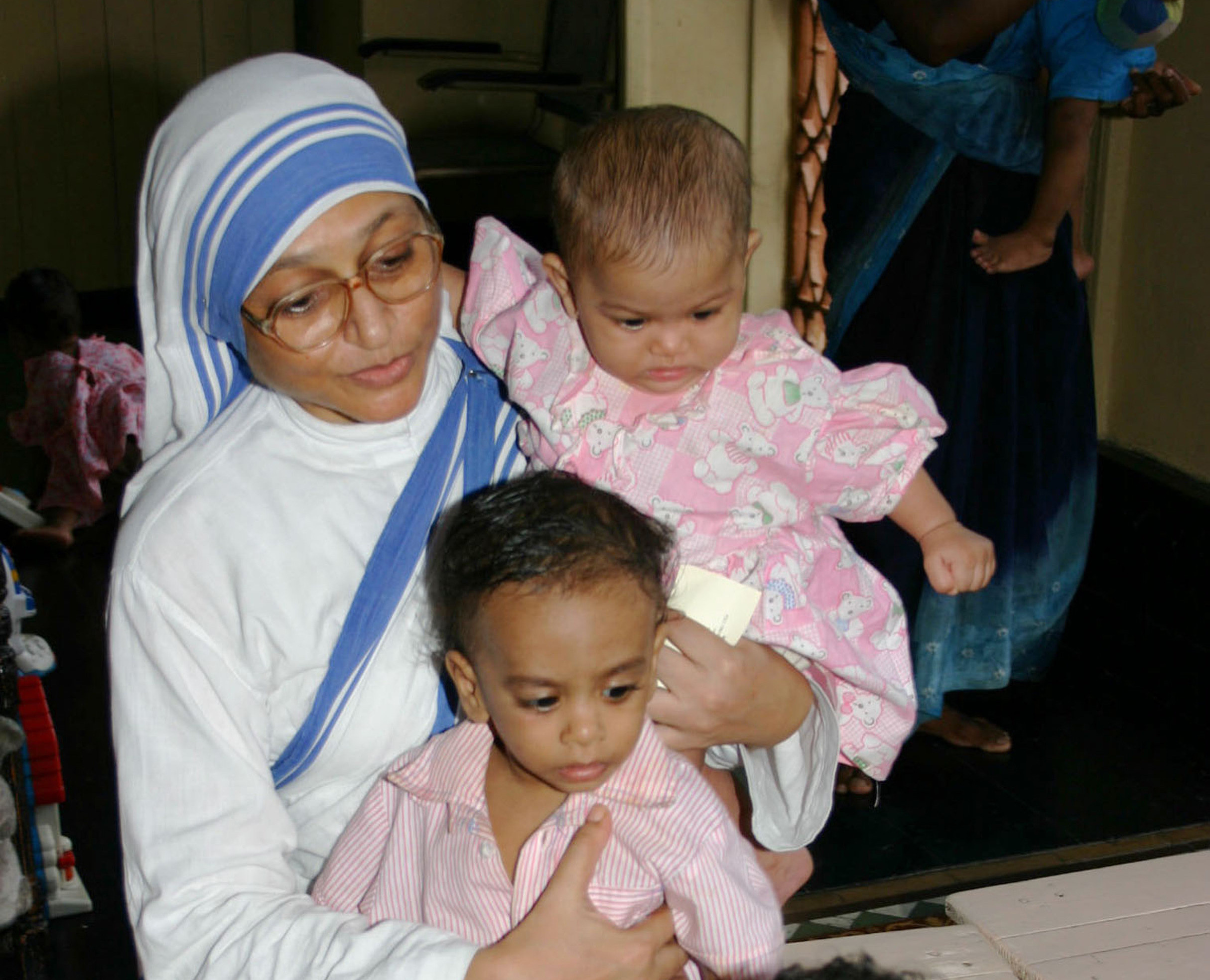 A member of the Missionaries of Charity holds orphan children in 2007 at a center in Kolkata, India. The Missionaries of Charity will close their adoption centers in India, citing new regulations that would allow nontraditional families to adopt children, reported ucanews.com. (CNS photo/Anto Akkara)