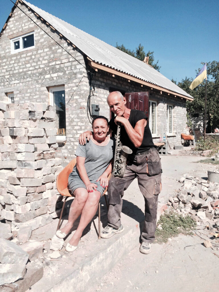Ira and Hennadiy pose for a photo in front of their destroyed home in Slovyansk Aug. 25. Volunteers from "Building Ukraine Together" helped them rebuild their house. (CNS photo/Pavlo Didula)