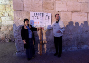 Peta Jones Pellach, an Orthodox Jewish woman who works for the Elijah Interfaith Institute, and Anglican Father Nicholas Taylor of Scotland, hold a sign at an interfaith prayer service for peace in the Old City of Jerusalem Oct. 29. (CNS photo/Debbie Hill)