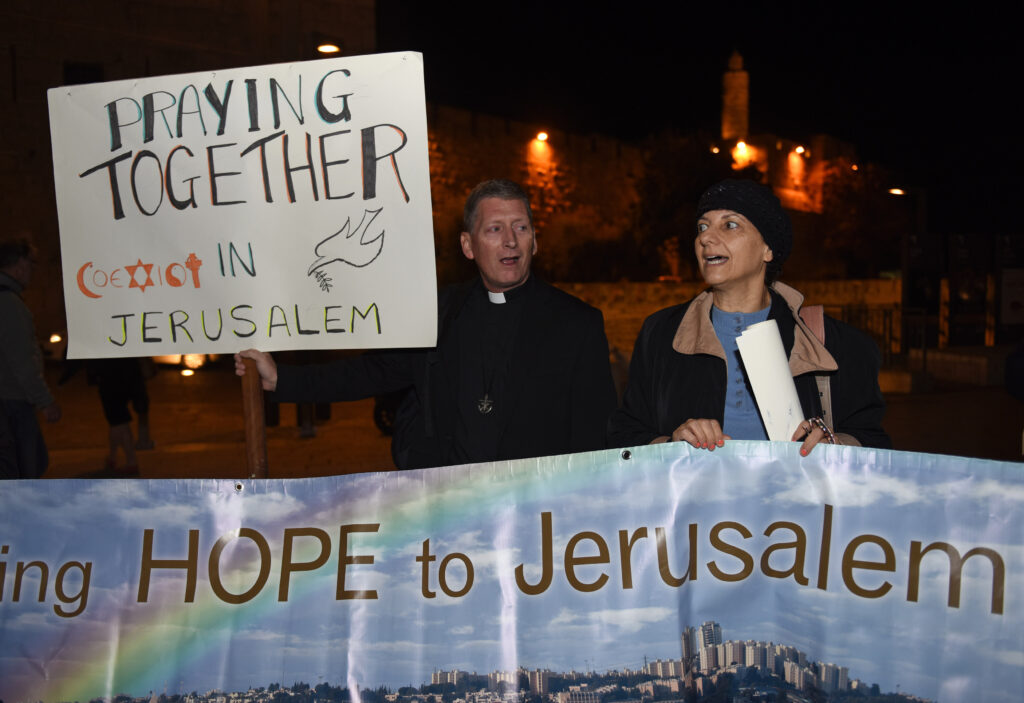 Holy Cross Father Russ McDougall, rector of Tantur Ecumenical Institute, and Peta Jones Pellach, an Orthodox Jewish woman who works for the Elijah Interfaith Institute, sing during an interfaith prayer service for peace in the Old City of Jerusalem Oct. 29. (CNS photo/Debbie Hill)