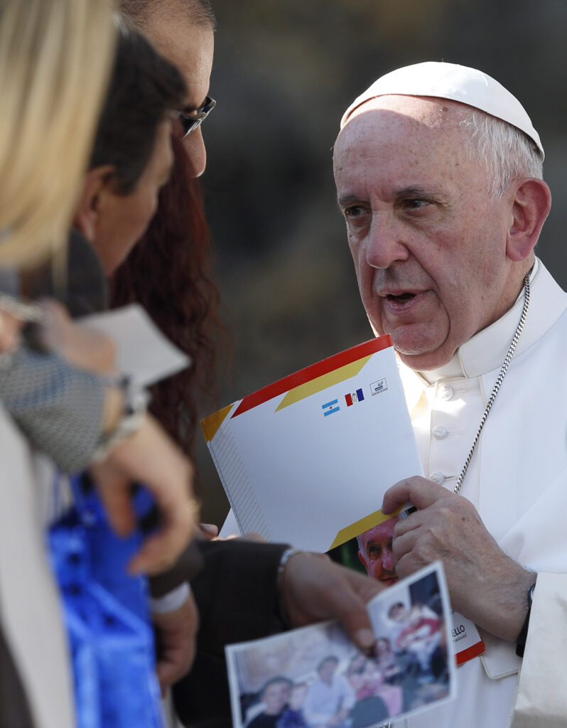 Pope Francis accepts materials from people as he greets the crowd during his general audience in St. Peter's Square at the Vatican Nov. 4. (CNS photo/Paul Haring)