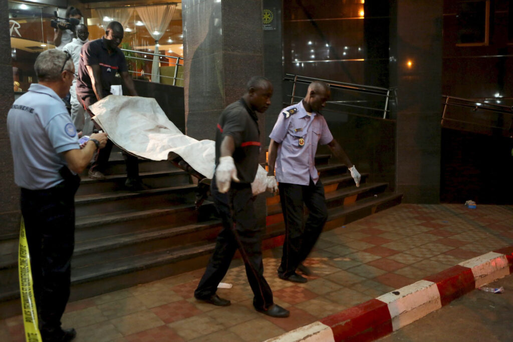 Officials carry a body outside the Radisson Hotel in Bamako, Mali, Nov. 20. At least 22 people were killed that day when gunmen raided the hotel and held 170 people hostage. (CNS photo/Joe Penney, Reuters)